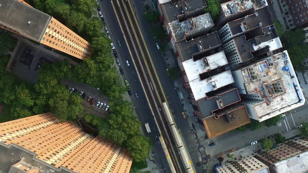 aerial of 1 train - subway riding on elevated track through Harlem with housing projects and rooftops in NYC