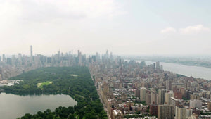Central Park aerial pulling backwards from buildings over green trees New York City NYC