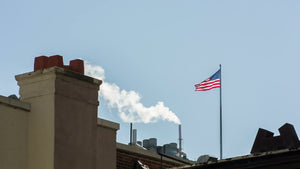 American flag on rooftop with steampipe blowing smoke in New York City