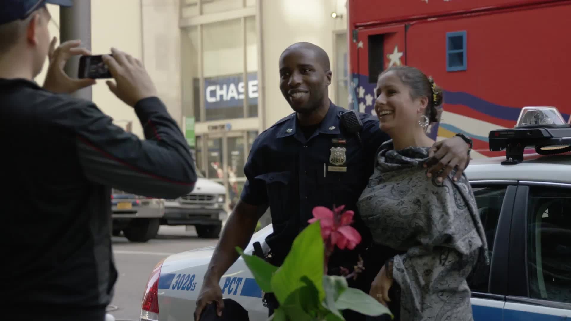 tourist woman taking picture with NYPD police officer - smiling for camera on summer day in NYC
