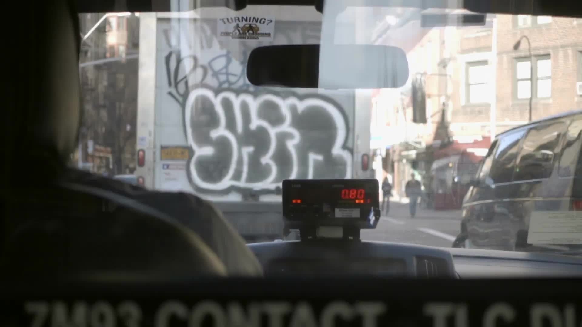 interior taxi cab with view of graffiti truck in windshield in Lower Manhattan NYC