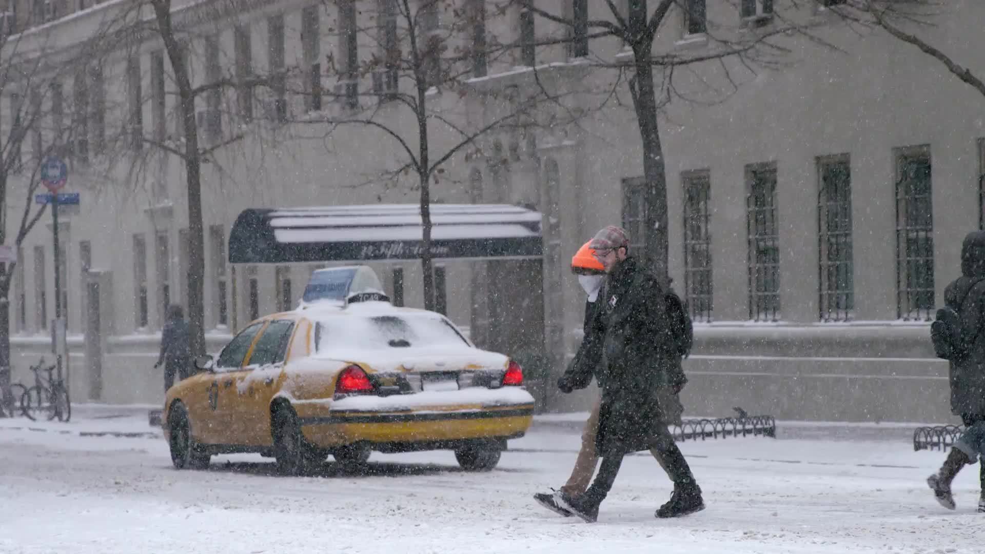 taxi cab driving in winter blizzard snow - people crossing street - snowing in Manhattan