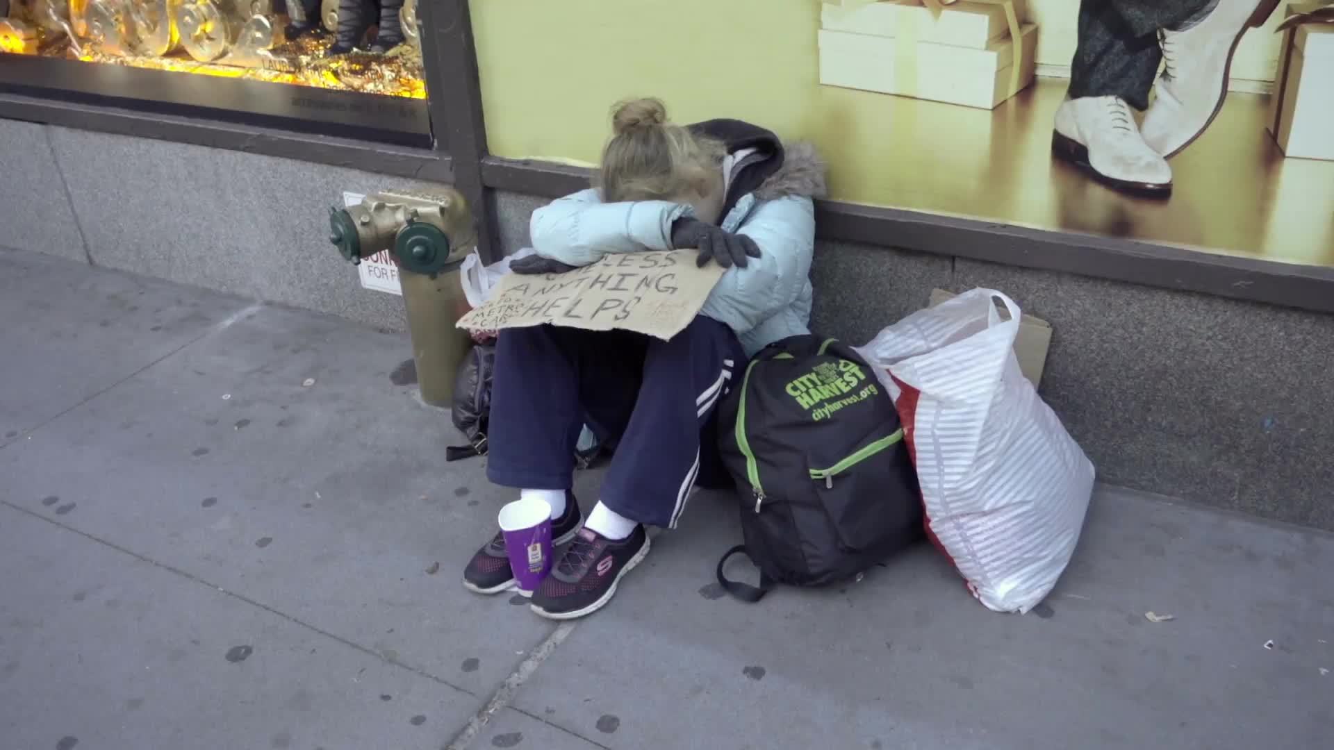 homeless woman with help sign sitting on sidewalk - hopeless and destitute in cold winter - New York City NYC 1080 HD