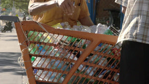 closeup of hand sorting dirty cans in shopping cart on street on sunny summer day - recycling in NYC
