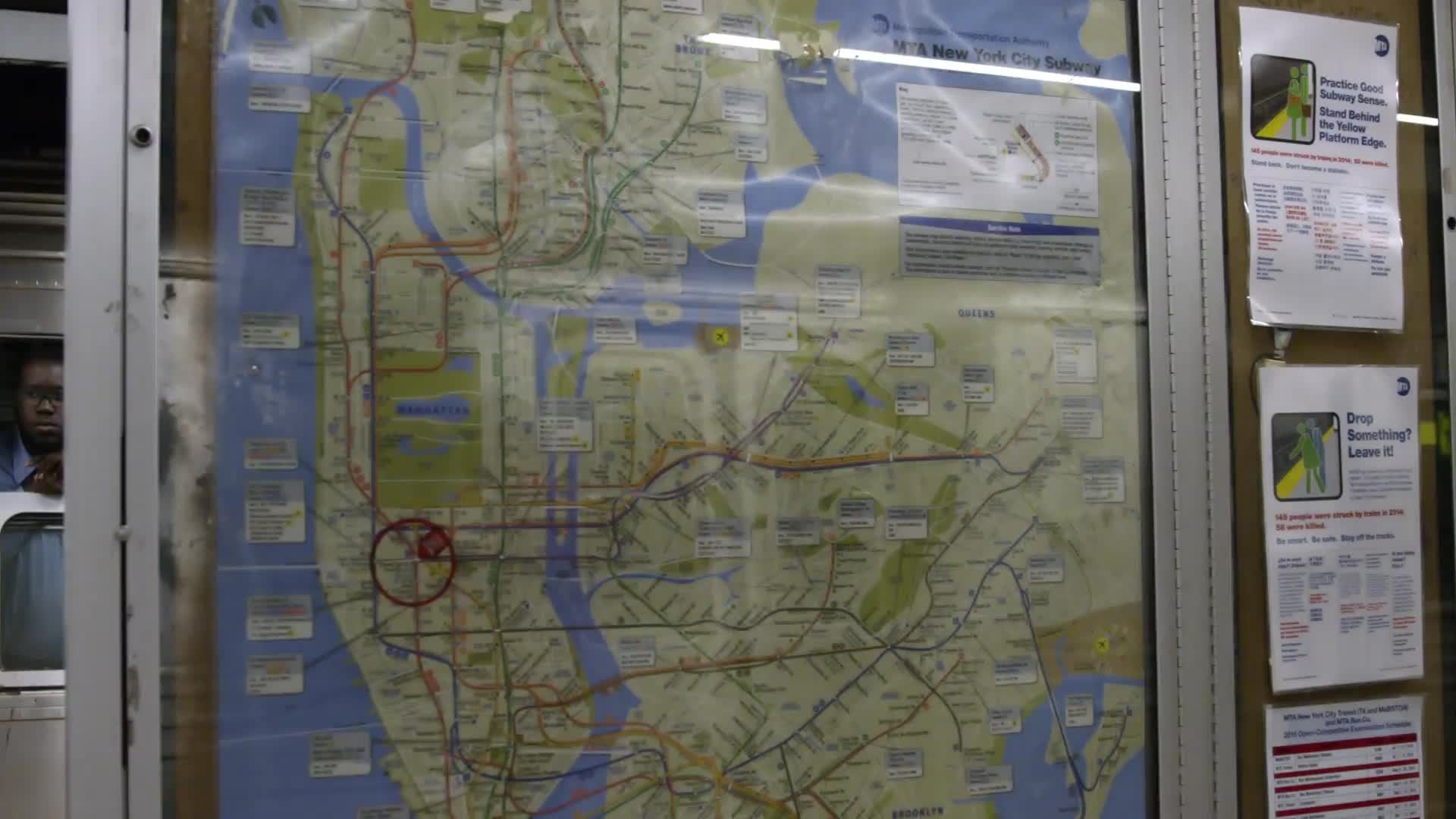 Times Square subway station sign tilting up from MTA city map - reflection of train moving
