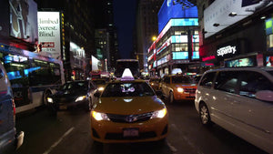 yellow taxi cab driving through Times Square at night in Manhattan