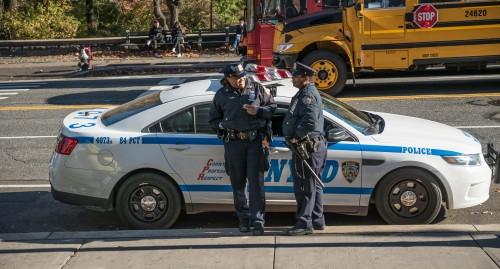 NYPD officers chatting leaning on police car on sunny Fall day in NYC