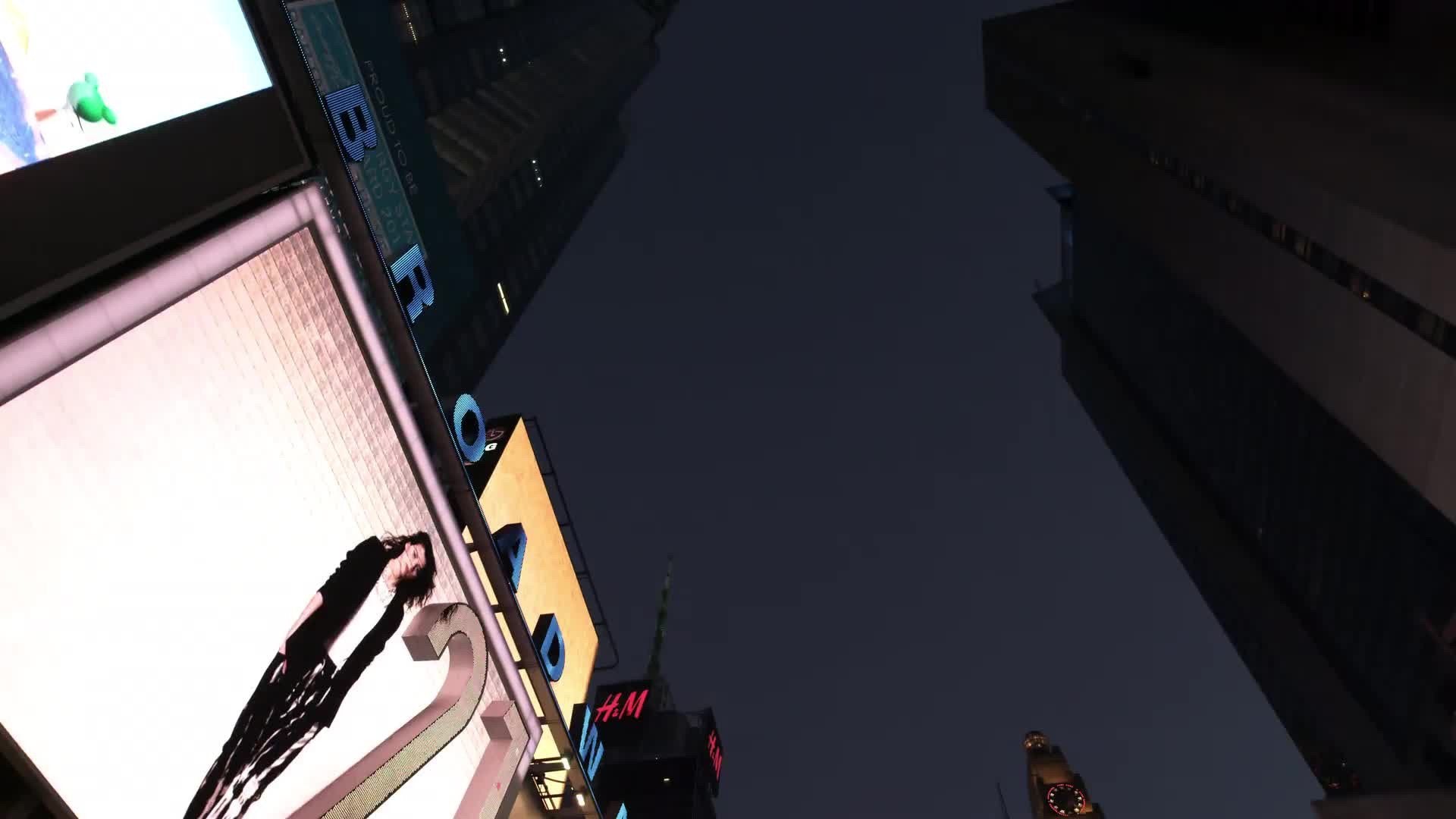 upward angle of animated digital billboards driving through Times Square at night