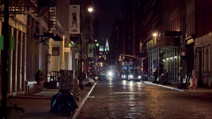 quiet cobblestone street in SoHo at night with Chrysler Building in background - two people crossing