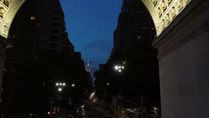 pulling back from Empire State Building through Washington Square Park arch at night NYC