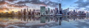 wide panoramic view of Manhattan skyline across East River with reflection of skyscrapers at sunset in NYC