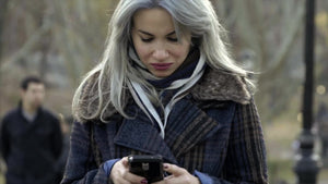 beautiful woman text message on smartphone in Central Park on cold fall winter day, in coat and scarf