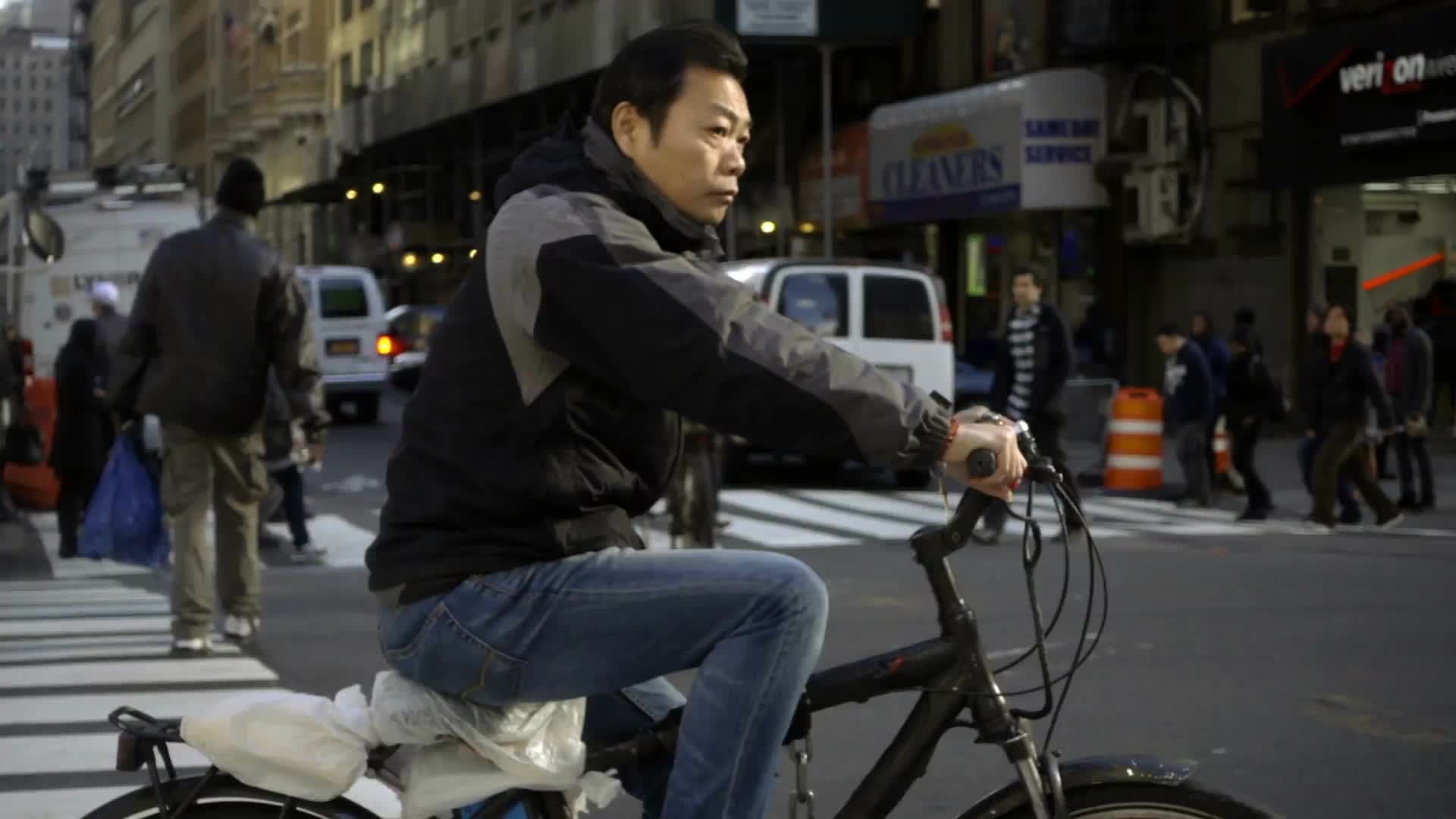 man on bicycle riding in street on fall day in Manhattan NYC - slow motion