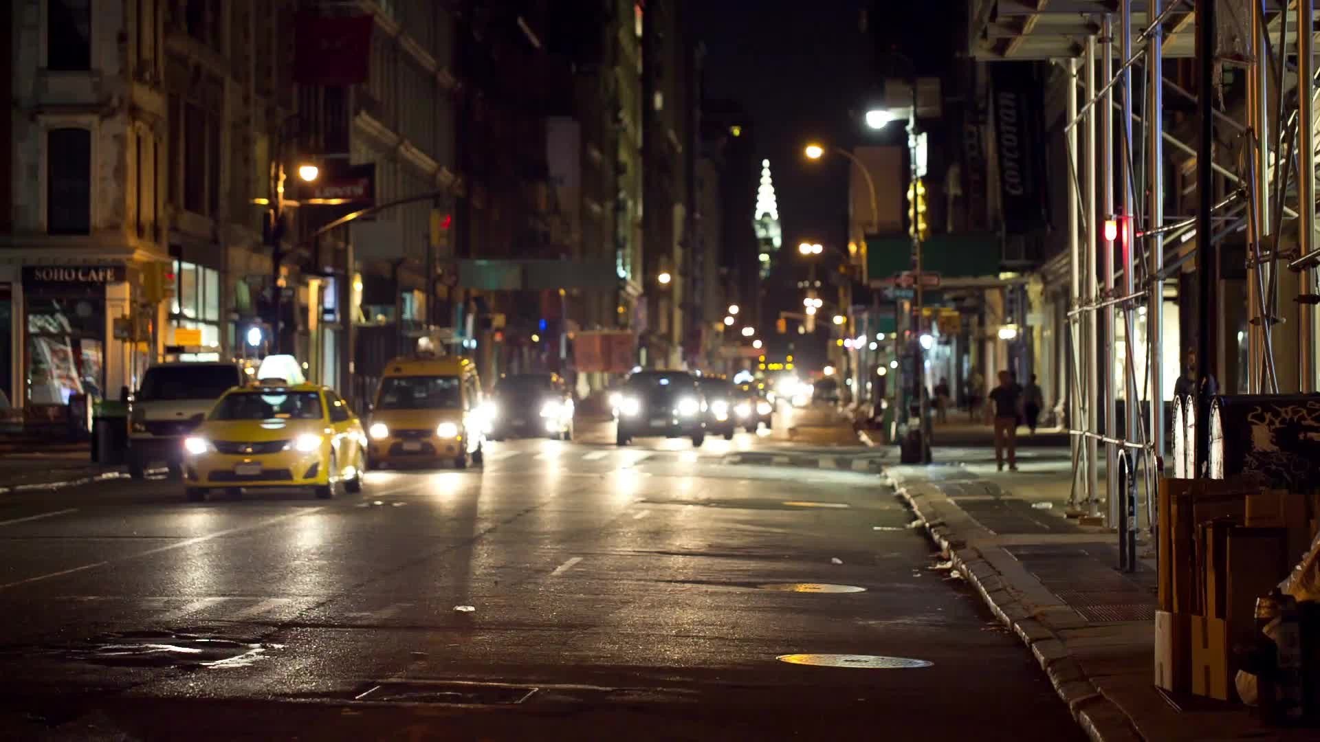 Chrysler Building in distance view from Downtown Broadway in SoHo at night, cars and taxis driving in Manhattan NYC