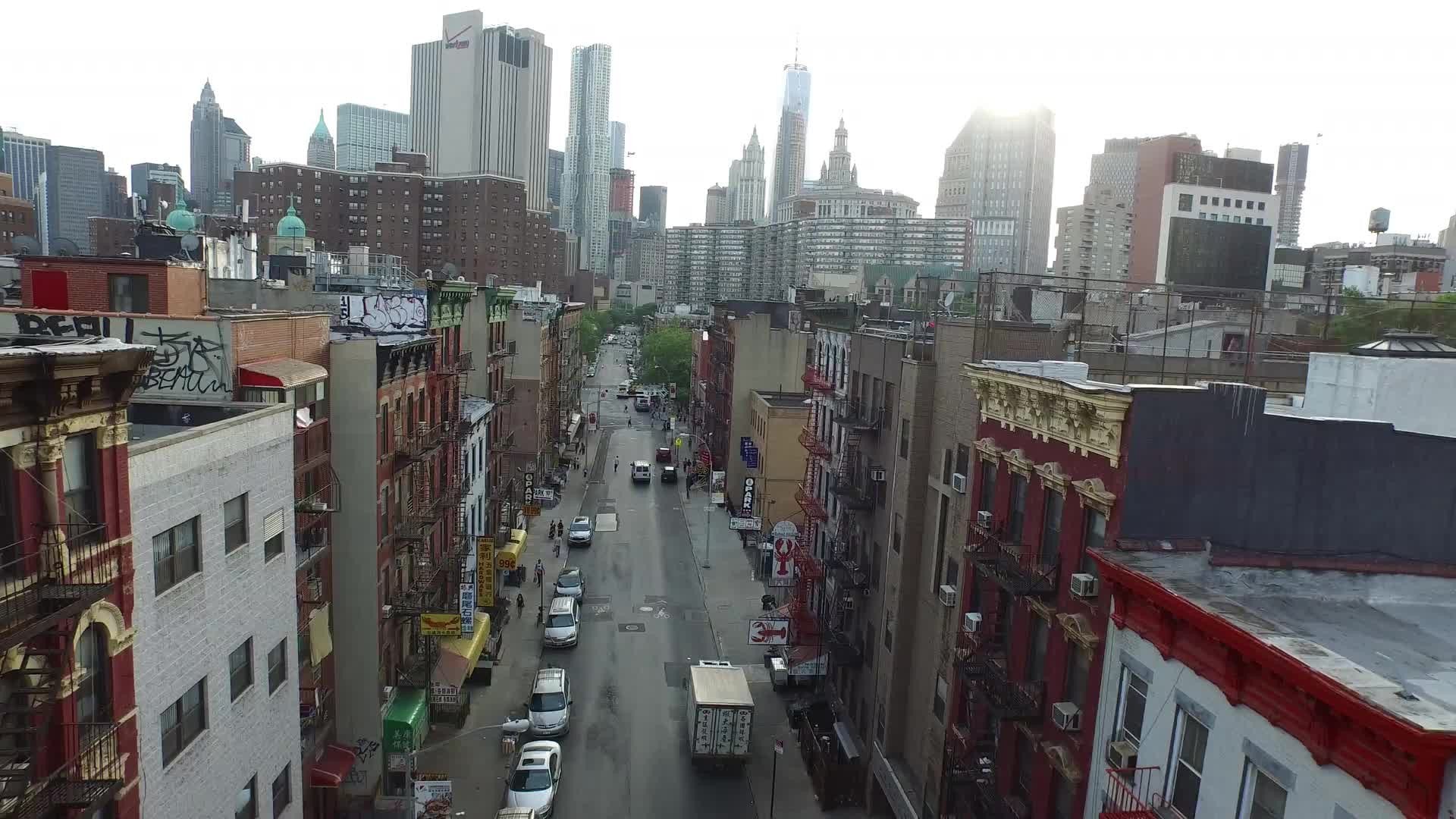 aerial over Chinatown street with skyscrapers in background in Lower Manhattan NYC