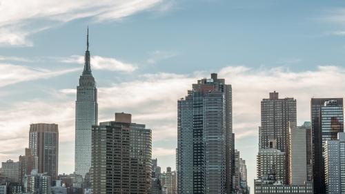 Empire State Building medium shot of Manhattan skyline early evening daytime beautiful clouds in sky New York City NYC