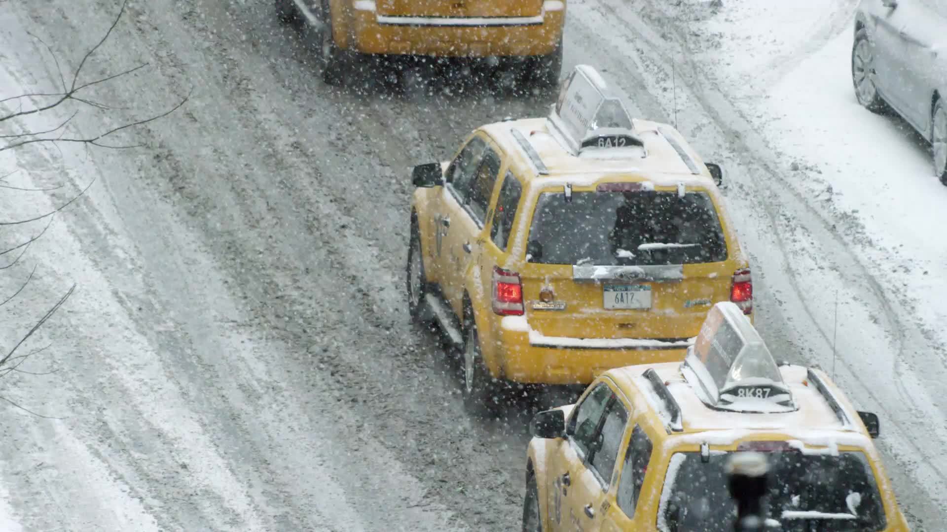 taxis in blizzard - cabs in traffic - taxicabs in winter snow storm street driving NYC