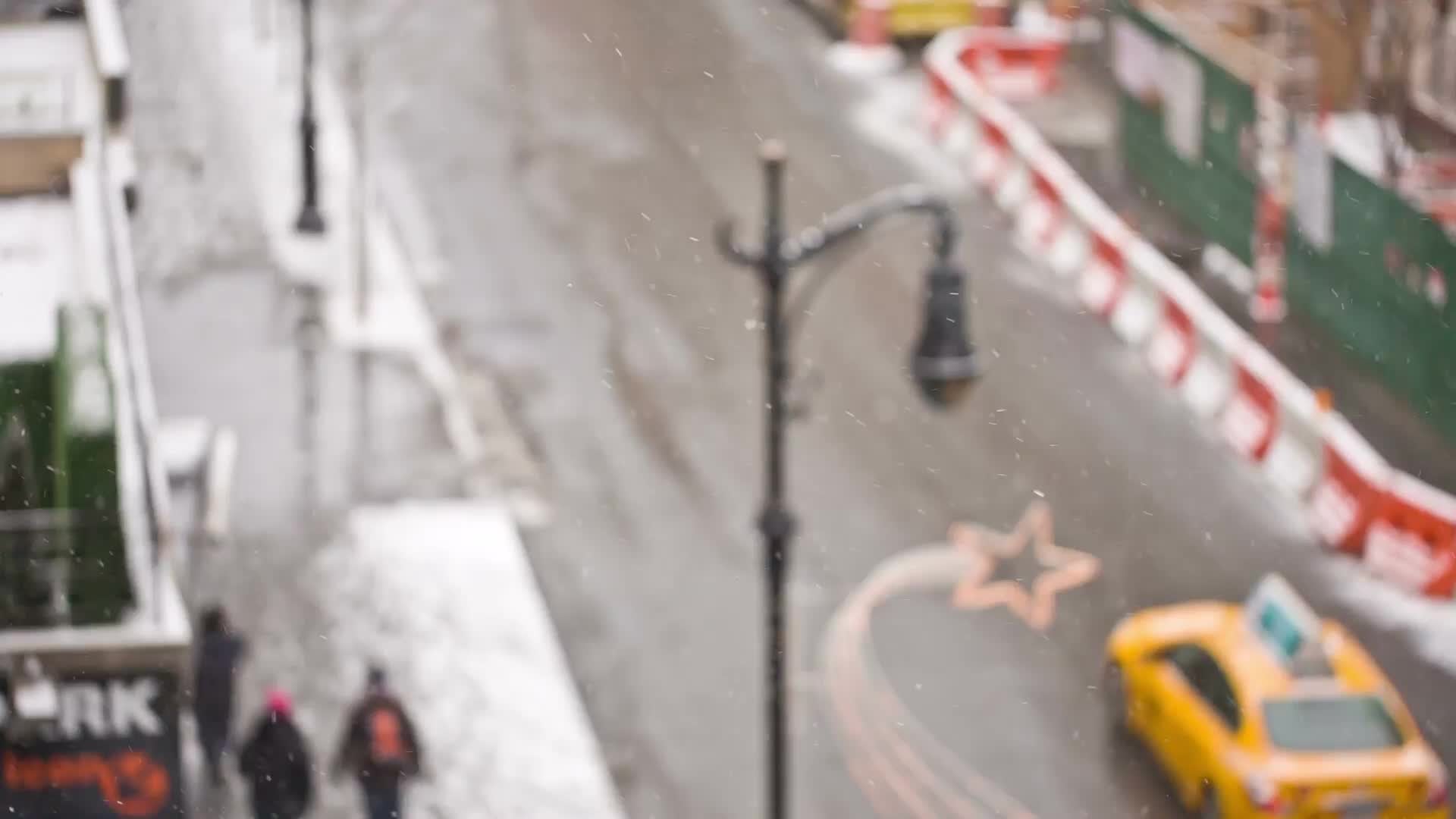 taxi cabs driving down winter street - bus in snow - people walking - snowing on holidays - overhead view