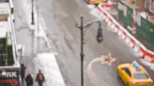 taxi cabs driving down winter street - bus in snow - people walking - snowing on holidays - overhead view