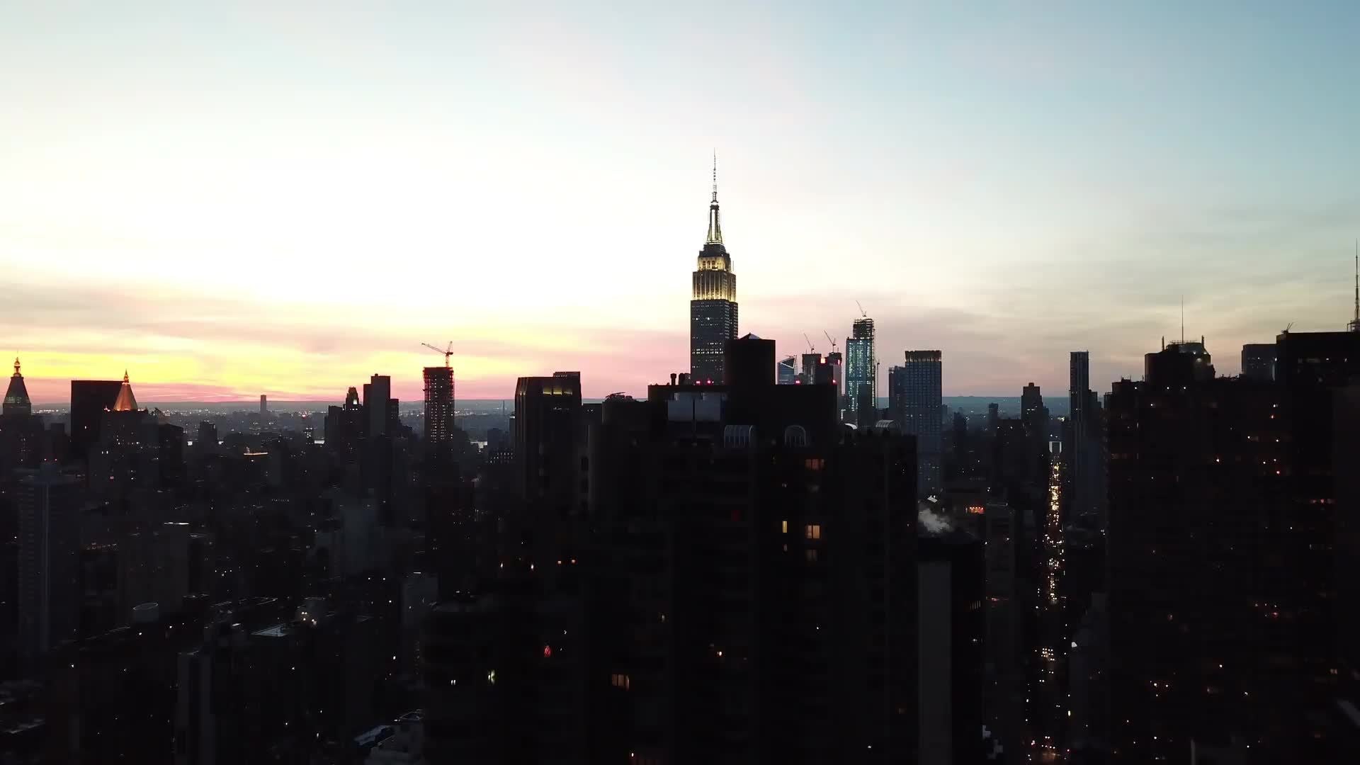 Empire State Building aerial shot moving over buildings and toward landmark skyscraper at sunset in Manhattan New York City NYC 4K and 1080 HD