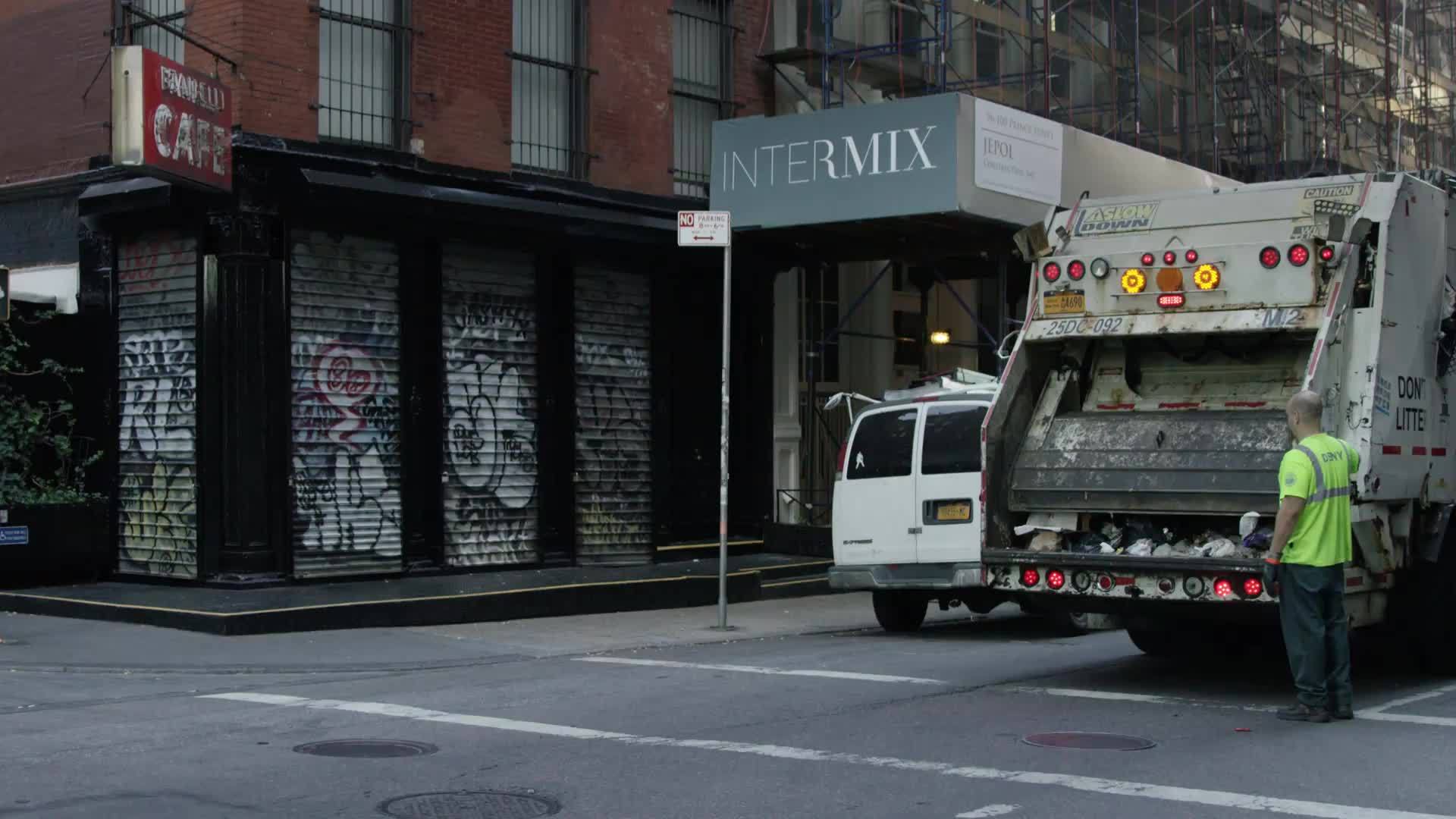 garbage truck on quiet empty street SoHo morning graffiti metal shutter gate over storefronts