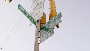 125th St and Amsterdam Ave sign tilting to Harlem housing projects uptown NYC