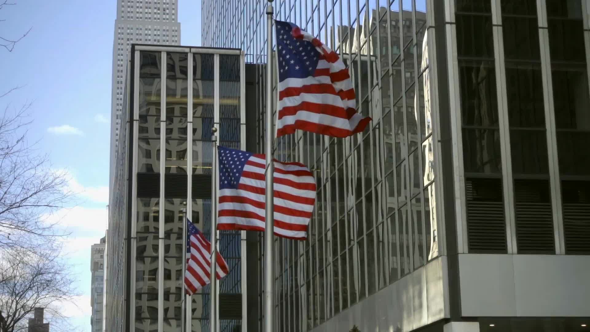 3 American flags waving in front of corporate buildings in Midtown Manhattan NYC