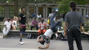 kid breakdancing - spinning on hand in Washington Square Park on summer day - slow motion