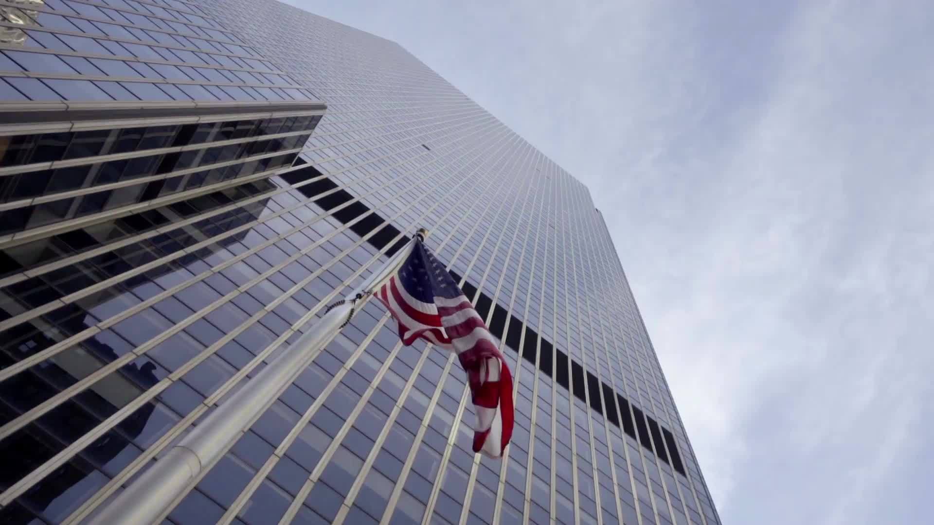 American flag waving upward angle skyscraper corporate building with sky in Midtown Manhattan New York City NYC 1080 HD