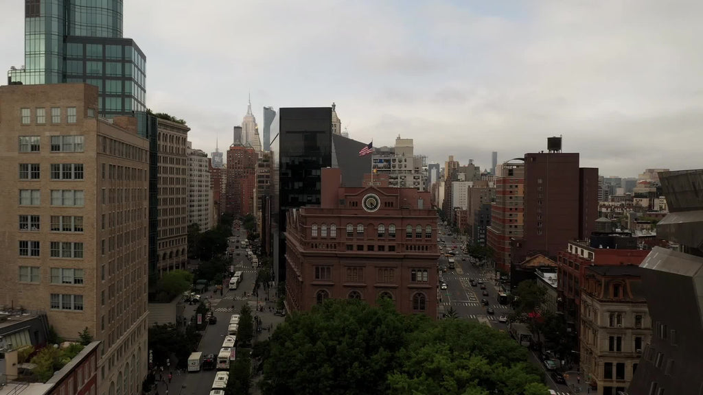 aerial flying over American flag and clock on Cooper Union building with cityscape above in Manhattan New York City NYC