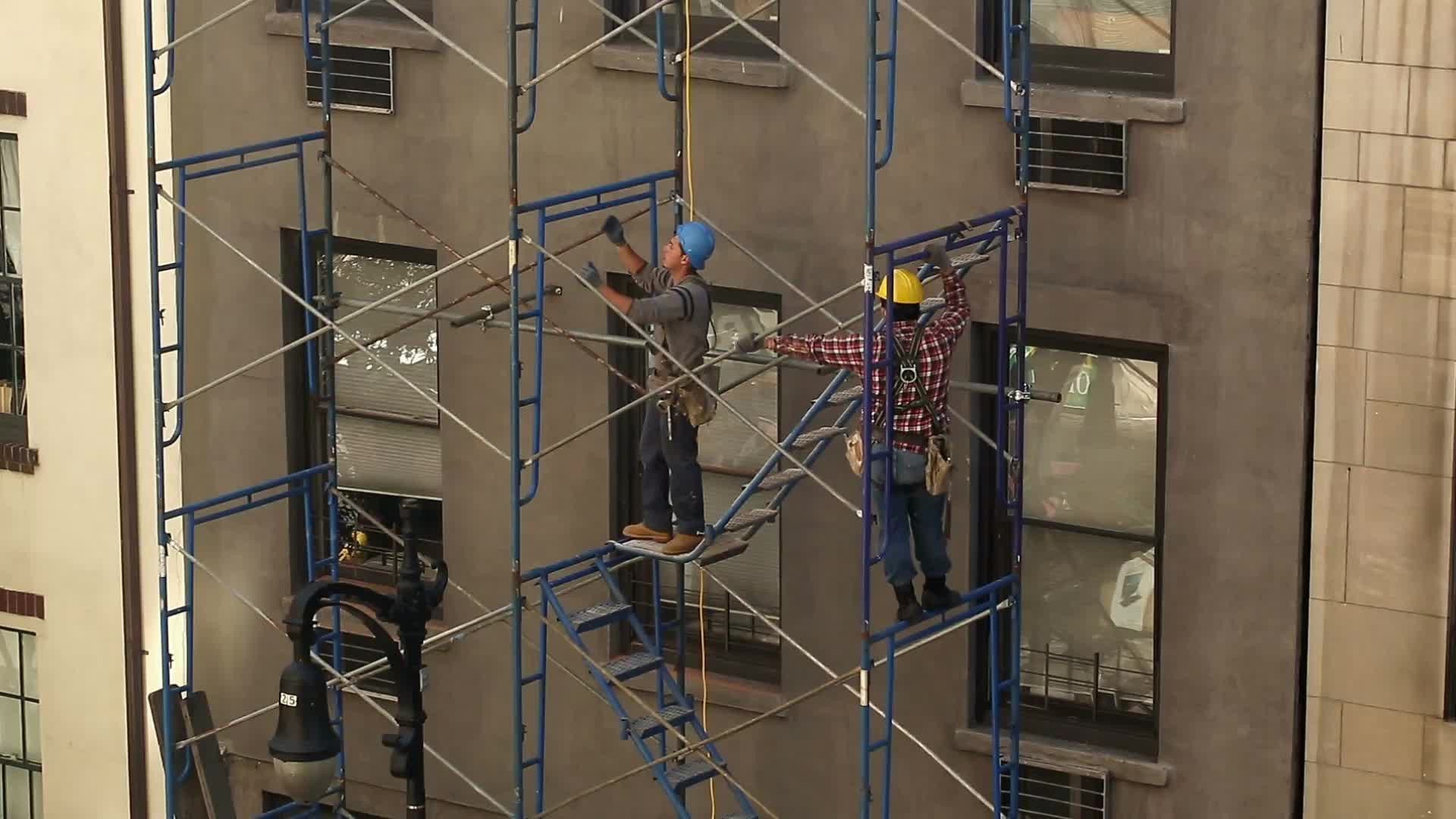 construction workers in hardhats on scaffolding - man doing pull-ups on his break in NYC