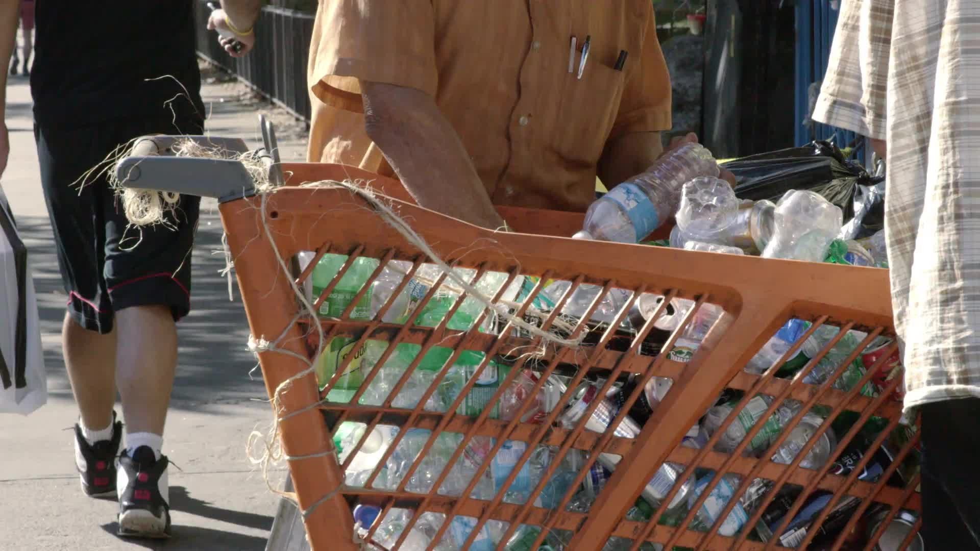 man collecting bottles in shopping cart uptown in gritty Harlem recycling station in 4K