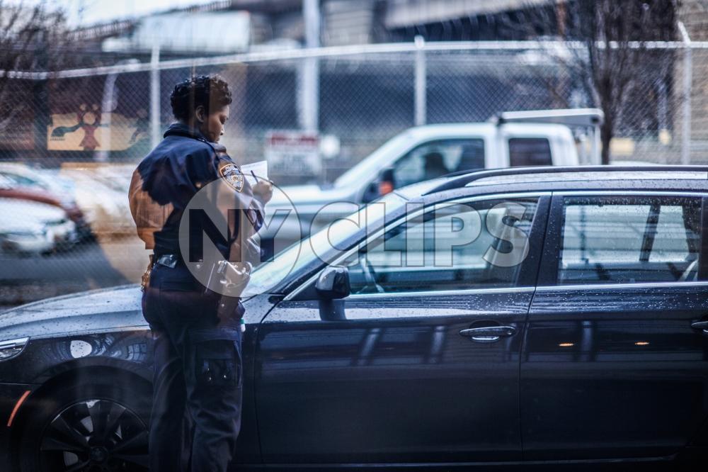 police officer writing parking ticket on street - female cop