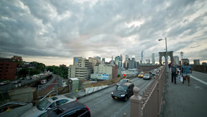 cars in traffic entering Brooklyn off bridge on summer evening - beautiful sunset clouds in NYC