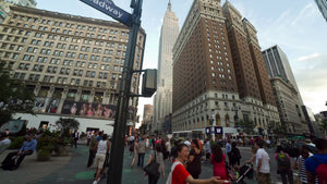 Broadway sign at Herald Square on summer day, tilting from street to Empire State Building