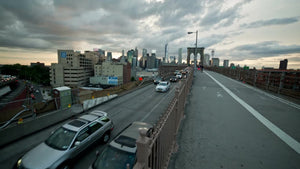 cars driving on Brooklyn Bridge from Manhattan, pedestrian path at sunset, summer evening in NYC