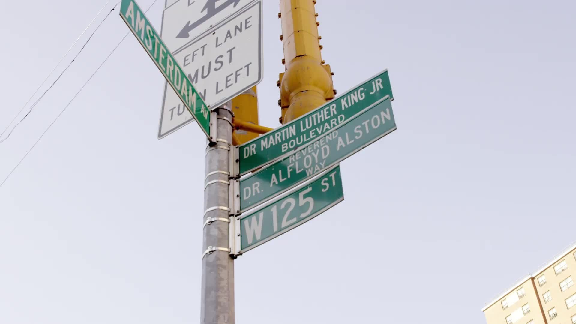 125th street sign with housing projects in background in Harlem on summer day in NYC