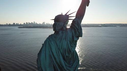Statue of Liberty back in New York Harbor - aerial over water in NYC