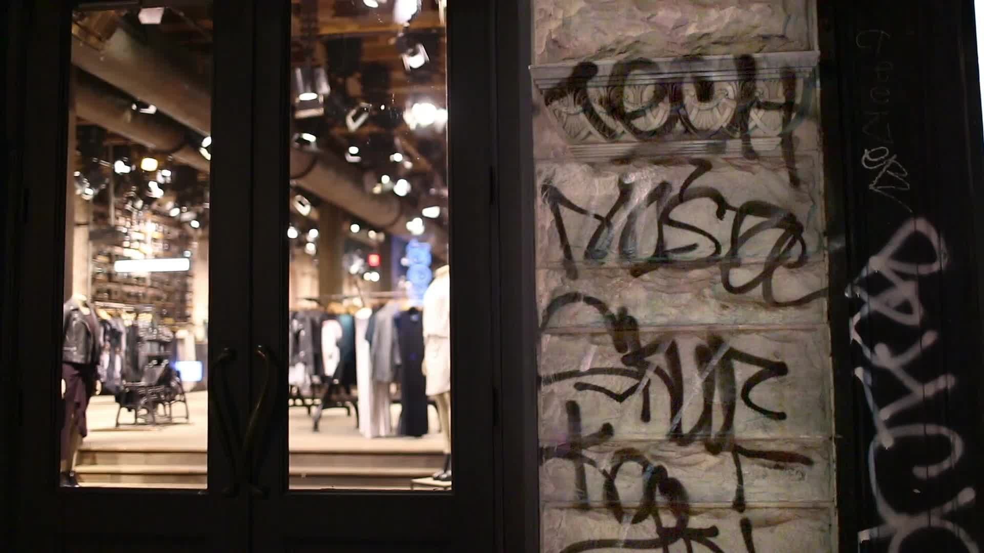 graffiti written on entrance of clothing store at night on Broadway with audio in NYC