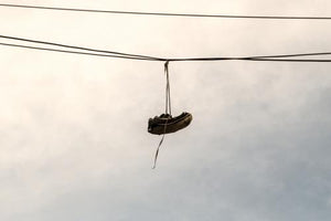 shoes dangling on wire - gritty sneakers hanging on cable - shoefetty