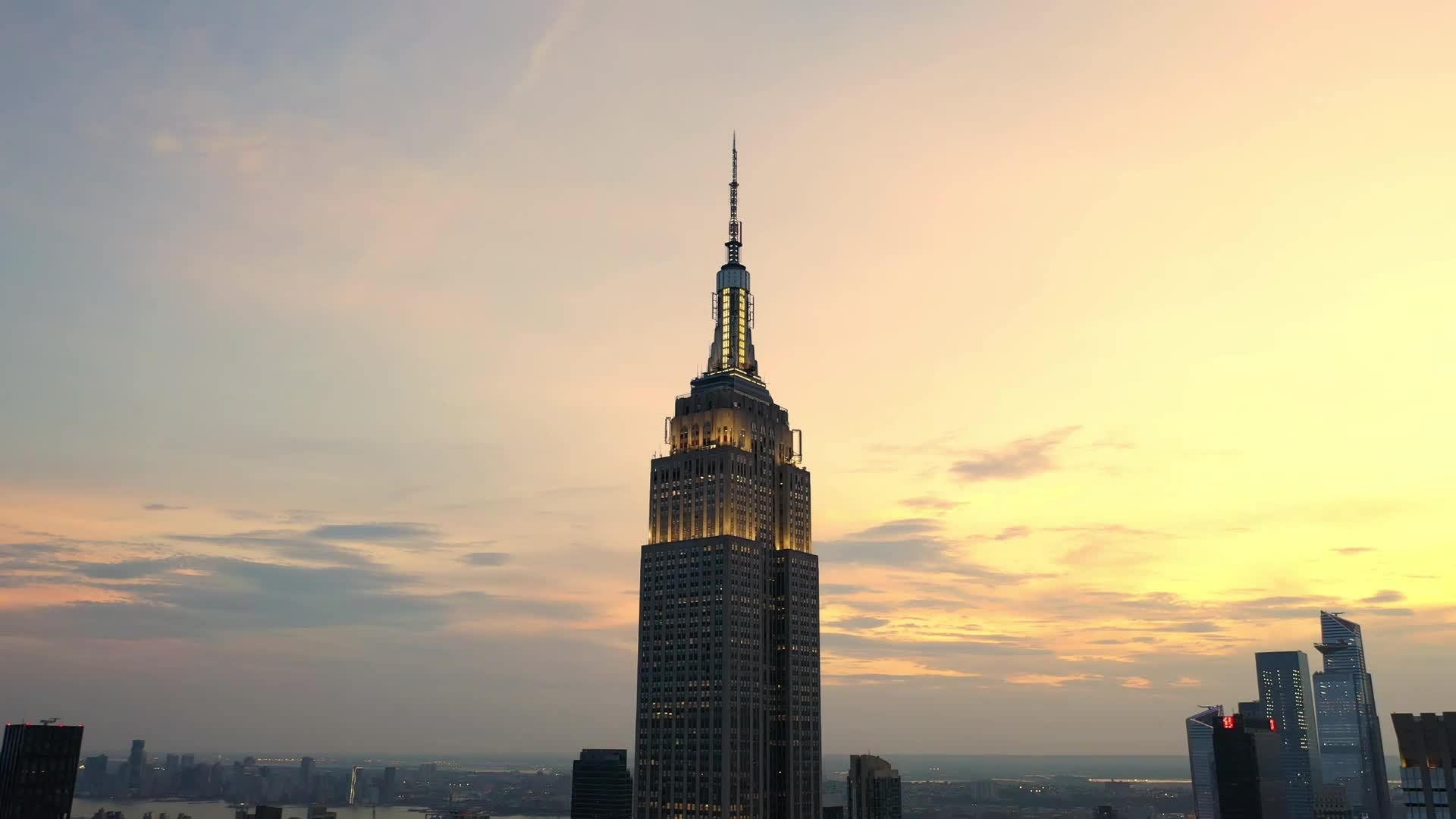 aerial circling Empire State Building at sunset colorful clouds in sky over famous skyscraper New York City NYC