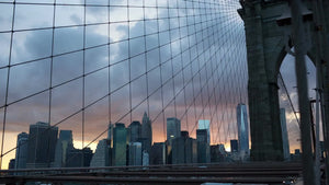 panning across Brooklyn Bridge at beautiful sunset - Manhattan skyline in background on summer day in early evening - NYC