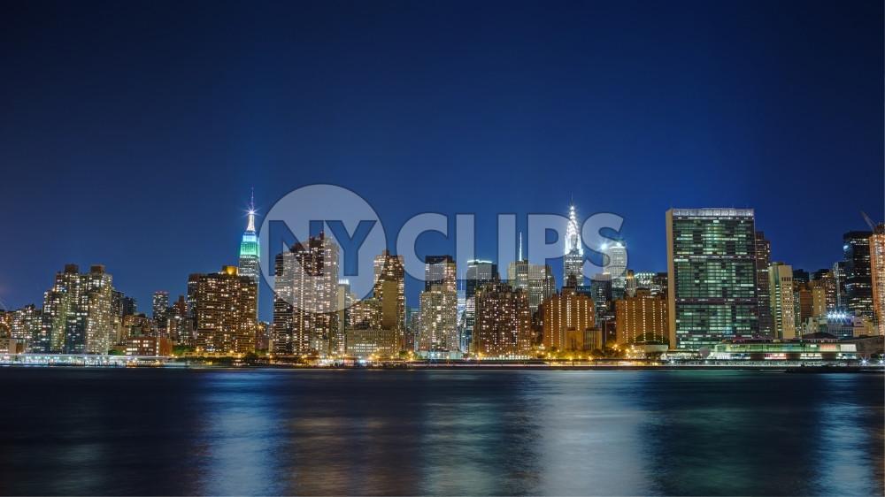 Manhattan skyline at night across East River water Empire State United Nations UN Chrysler Building skyscrapers lights NYC