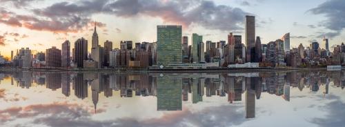 Manhattan Island on Water - Skyscrapers at sunset with Reflection - Empire State Building and United Nations, East River Panorama