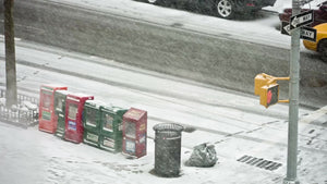 newspaper dispensers and garbage can on corner in snow storm - snowing winter blizzard