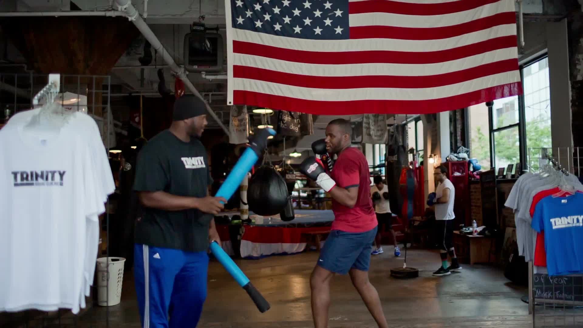 man training, boxing at Trinity Boxing Club in Financial District - boxer working out with trainer in gym with American flag