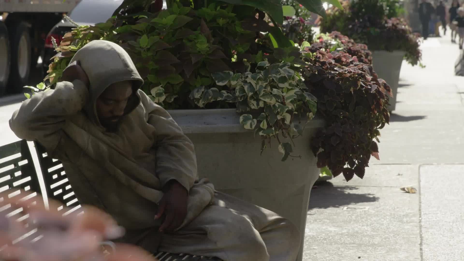 homeless man sleeping on bench on sunny summer day in NYC