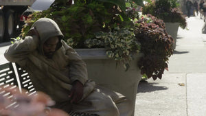 homeless man sleeping on bench on sunny summer day in NYC