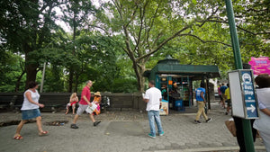 bus stop on Central Park West at Columbus Circle people walking man standing green summer trees