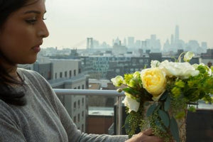 Brooklyn woman arranging flowers on rooftop with Manhattan skyline in background in New York City